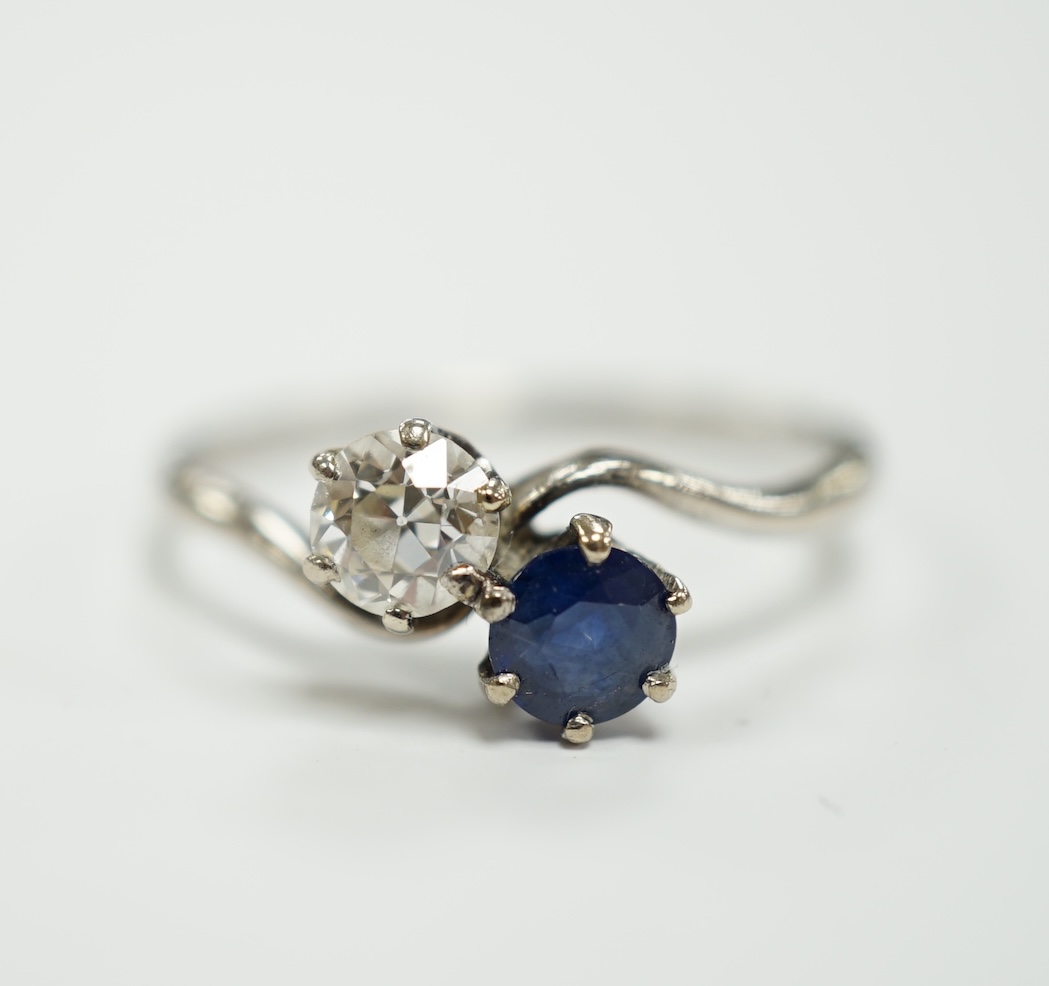 A mid 20th century white metal (stamped plat), sapphire and diamond set two stone crossover ring, size Q, gross weight 3.2 grams.